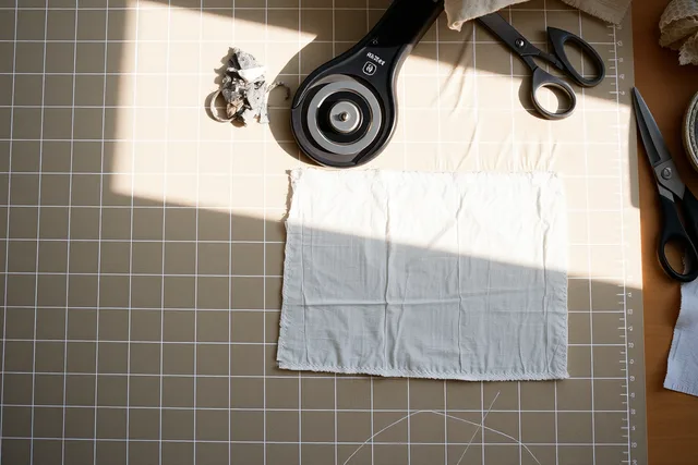 Rotary cutter slicing fabric on a scored self-healing cutting mat. Cutting and pressing surfaces for a mending kit, compared for wear